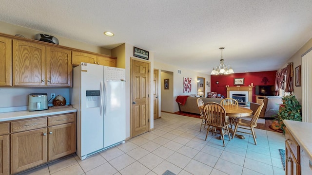 kitchen with white refrigerator with ice dispenser, open floor plan, a fireplace, and light countertops