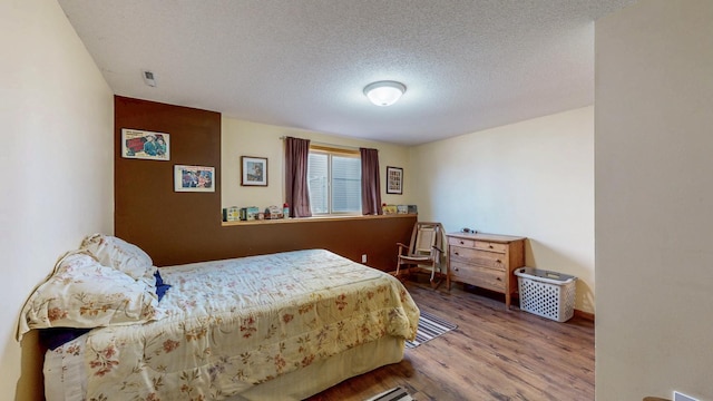 bedroom featuring a textured ceiling and wood finished floors