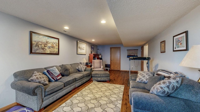 living area with recessed lighting, wood finished floors, baseboards, and a textured ceiling