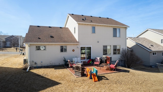 back of property featuring a lawn, a shingled roof, and a patio area