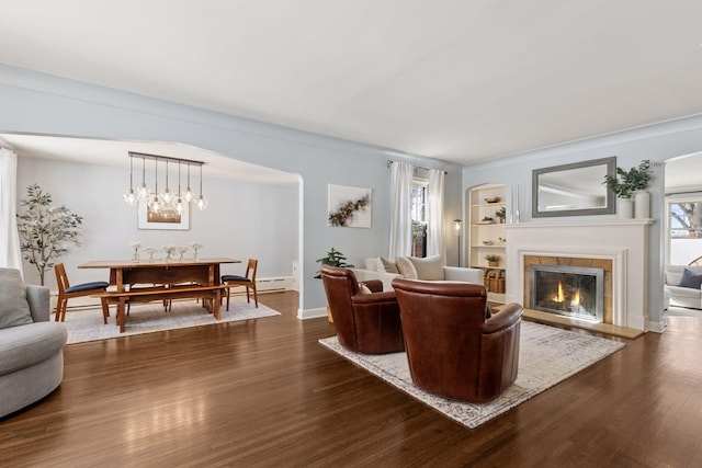 living area with built in features, baseboards, a fireplace, and dark wood-style flooring