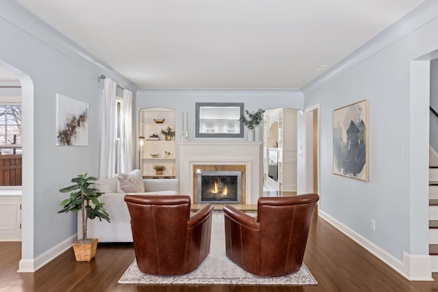 sitting room featuring a glass covered fireplace, stairway, dark wood-type flooring, and baseboards