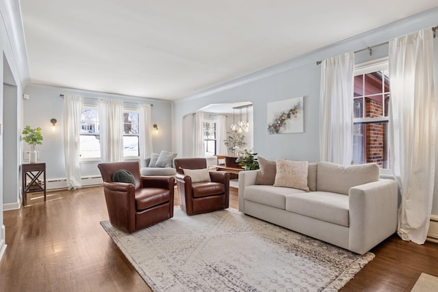 living area featuring a wealth of natural light, a chandelier, arched walkways, and wood finished floors