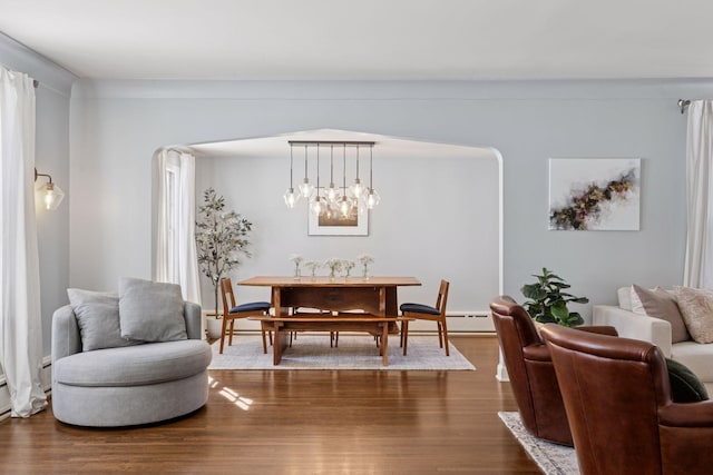 dining room featuring dark wood finished floors, baseboard heating, and arched walkways