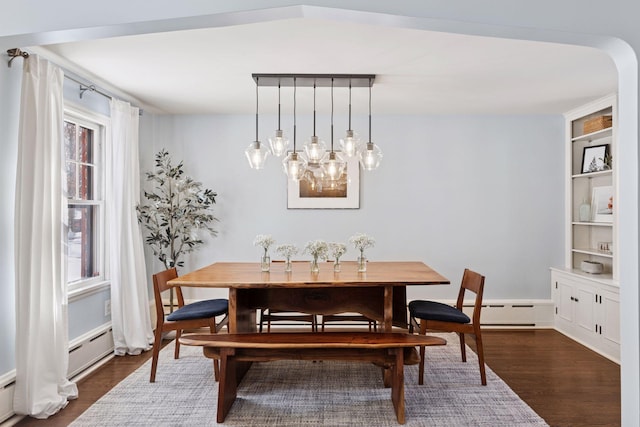 dining area with dark wood finished floors, built in shelves, and a baseboard heating unit