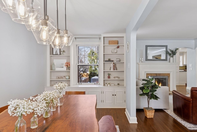 dining area with arched walkways, dark wood finished floors, and a tile fireplace