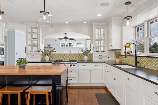 kitchen with white cabinetry, glass insert cabinets, backsplash, and a sink