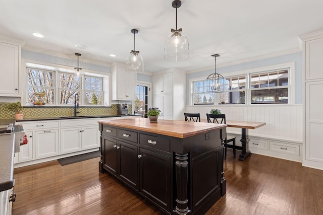 kitchen with wood counters, white cabinetry, dark cabinetry, and a sink