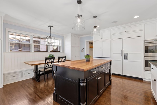 kitchen featuring double oven, butcher block counters, white cabinets, and paneled built in refrigerator