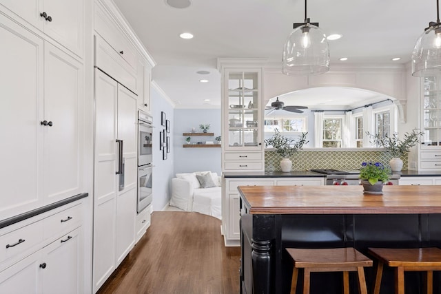 kitchen featuring tasteful backsplash, wooden counters, glass insert cabinets, crown molding, and white cabinetry