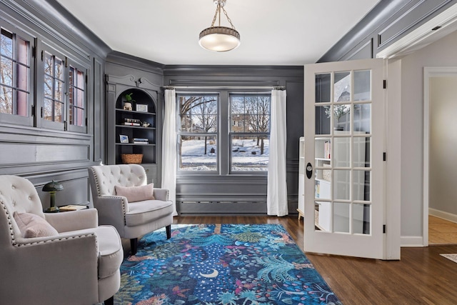 living area featuring built in shelves, wood finished floors, and baseboards