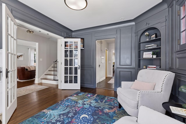 living area with dark wood finished floors, stairs, french doors, and built in shelves