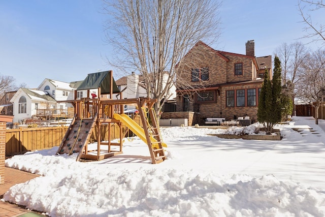 snow covered playground with a residential view, a playground, and fence