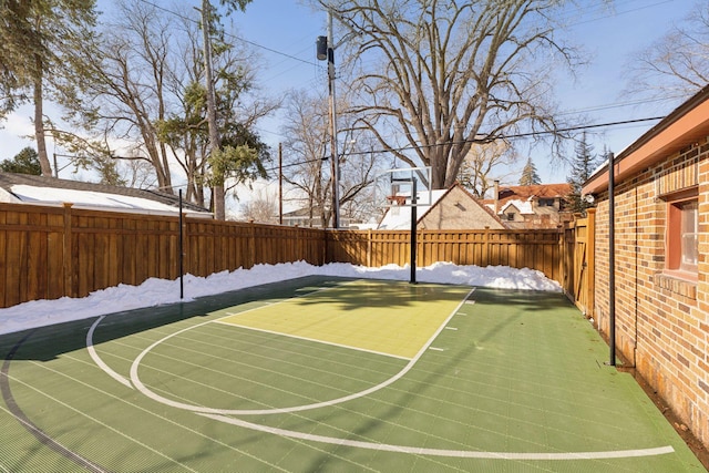 view of basketball court with basketball hoop and a fenced backyard