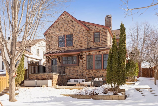 view of front facade featuring an outdoor living space, brick siding, a chimney, and fence