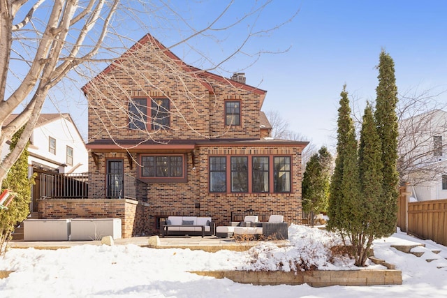 view of front of property featuring an outdoor hangout area, brick siding, a chimney, and fence