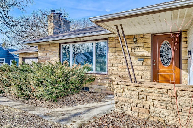 doorway to property with stone siding and a chimney