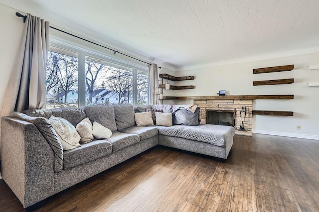 living room featuring dark wood-type flooring, a fireplace, baseboards, and a textured ceiling