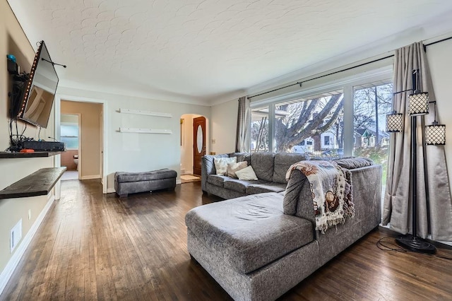 living room featuring visible vents, dark wood-type flooring, baseboards, arched walkways, and a textured ceiling