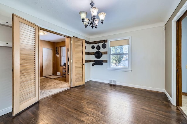 unfurnished room featuring wood finished floors, visible vents, a chandelier, and baseboards