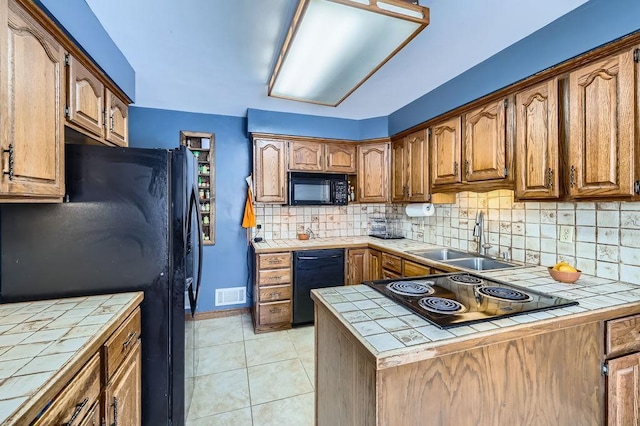 kitchen with visible vents, tile countertops, black appliances, and a sink