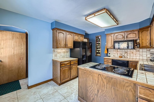 kitchen with decorative backsplash, black appliances, tile counters, and light tile patterned flooring