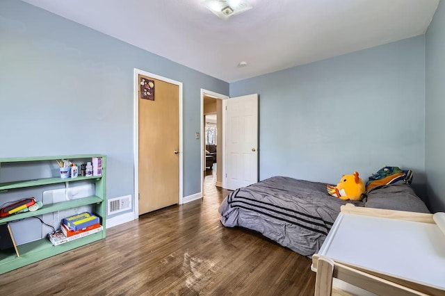 bedroom featuring visible vents, baseboards, and wood finished floors