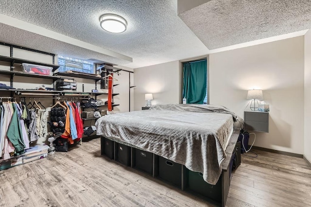 bedroom with wood finished floors, baseboards, and a textured ceiling