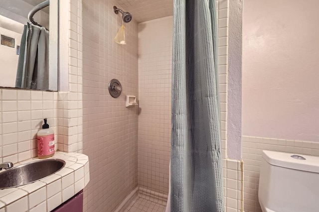 full bathroom with tile walls, toilet, and a shower stall