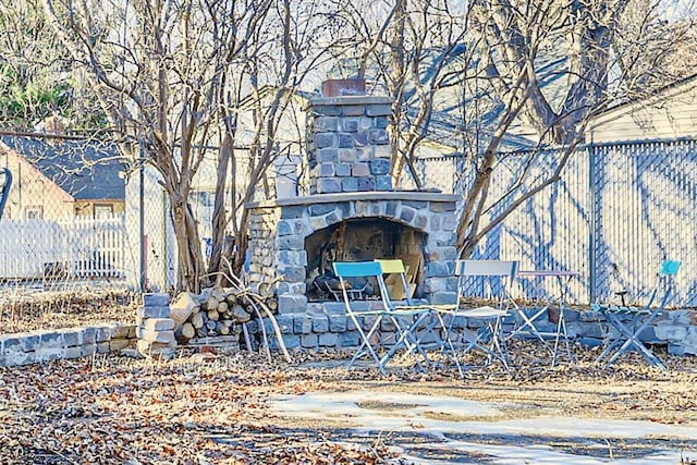 exterior space featuring stone siding, a fireplace, and fence