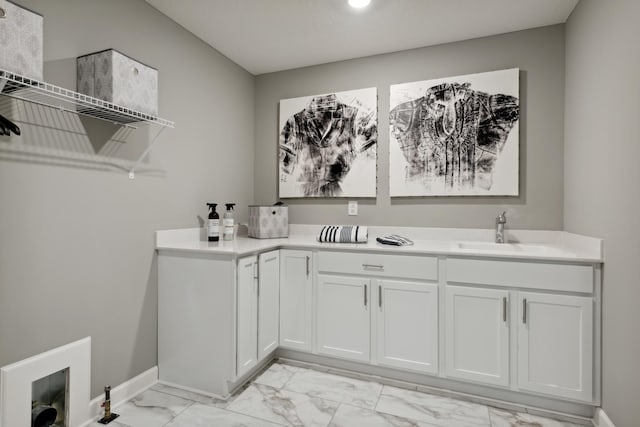 clothes washing area with marble finish floor, baseboards, and a sink