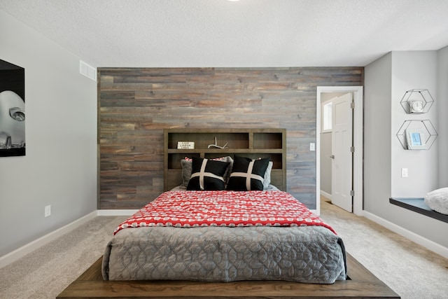 bedroom featuring wooden walls, carpet floors, a textured ceiling, and an accent wall