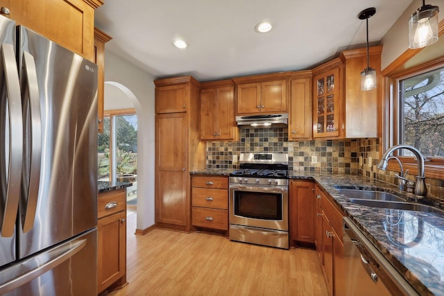 kitchen with a sink, stainless steel appliances, brown cabinets, and under cabinet range hood