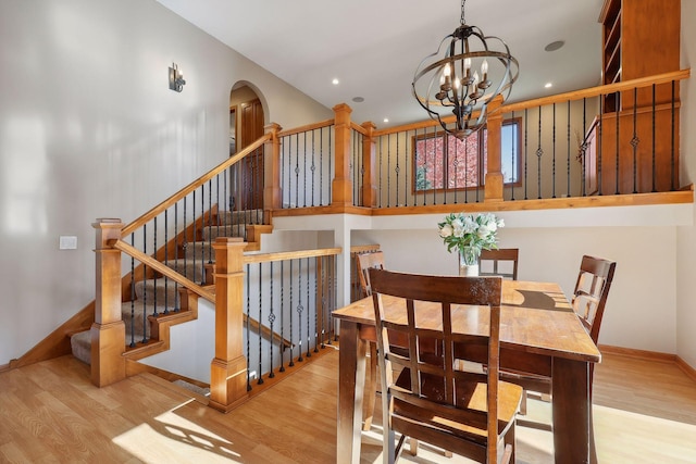 dining room with wood finished floors, baseboards, arched walkways, stairs, and a chandelier