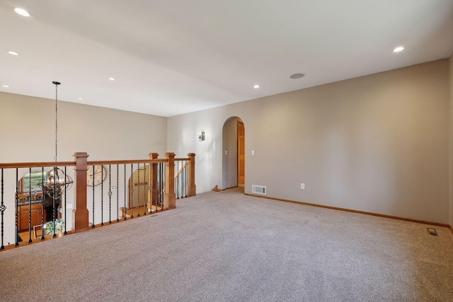 spare room featuring visible vents, baseboards, recessed lighting, arched walkways, and light colored carpet