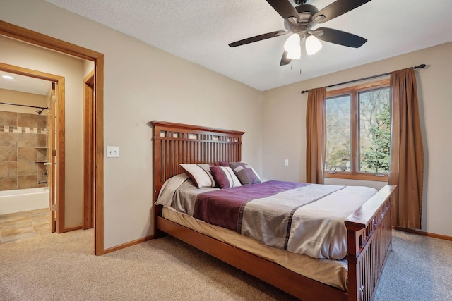 bedroom with baseboards, ceiling fan, light colored carpet, ensuite bathroom, and a textured ceiling