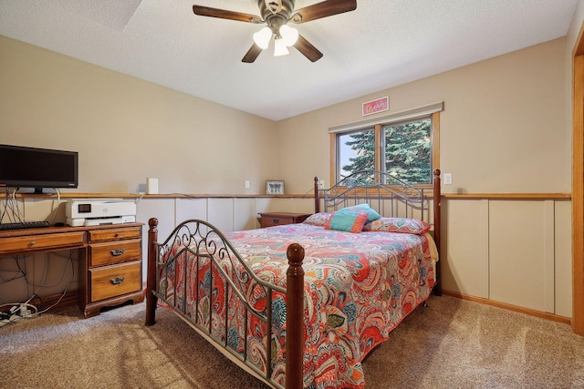 bedroom featuring carpet flooring, a textured ceiling, and a wainscoted wall