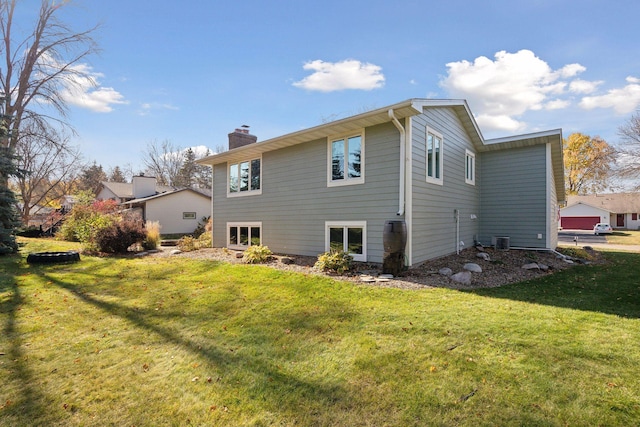 rear view of property with central air condition unit, a lawn, and a chimney