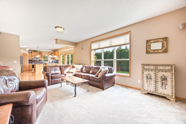 living room with light carpet, visible vents, a textured ceiling, and an inviting chandelier