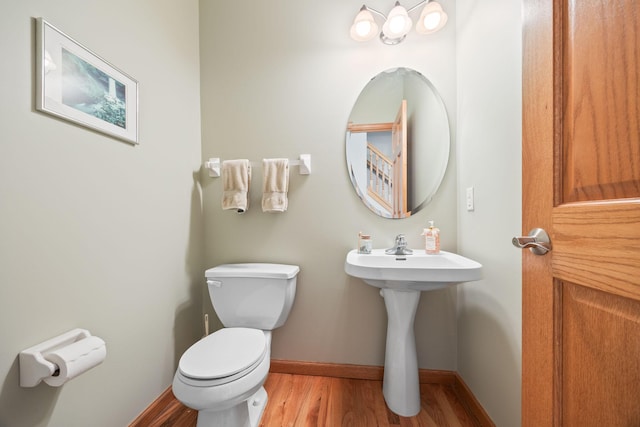 bathroom with toilet, baseboards, and wood finished floors