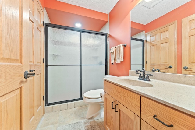 full bath featuring tile patterned floors, toilet, a stall shower, a textured ceiling, and vanity