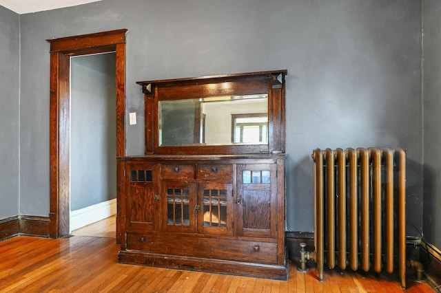 interior space with baseboards, radiator, and wood finished floors