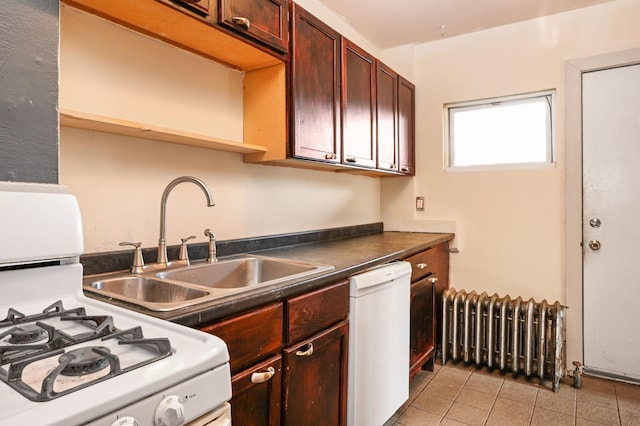 kitchen featuring dark countertops, radiator heating unit, light tile patterned floors, white appliances, and a sink