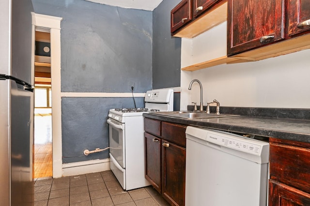 kitchen with white appliances, a sink, tile patterned flooring, dark countertops, and reddish brown cabinets