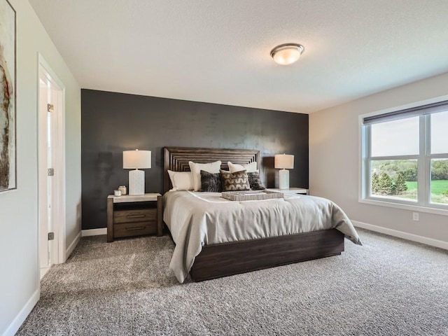 bedroom featuring an accent wall, baseboards, carpet floors, and a textured ceiling