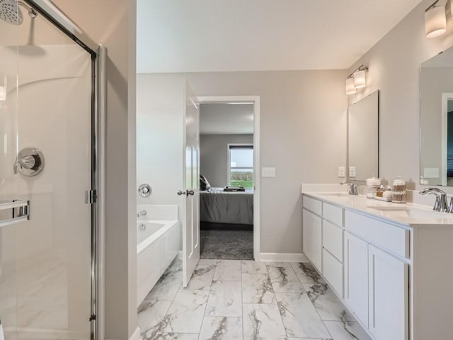 ensuite bathroom with a shower stall, a garden tub, marble finish floor, and a sink