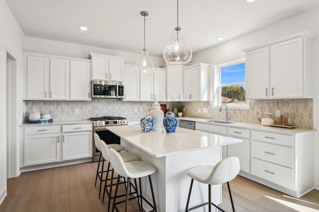 kitchen featuring a sink, a kitchen breakfast bar, a center island, appliances with stainless steel finishes, and white cabinets