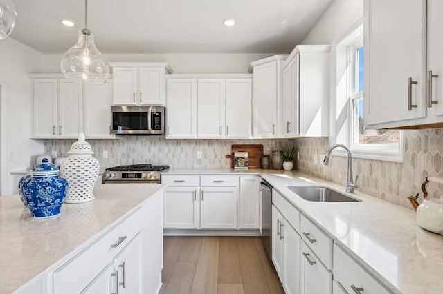 kitchen featuring a sink, tasteful backsplash, appliances with stainless steel finishes, white cabinets, and light wood finished floors