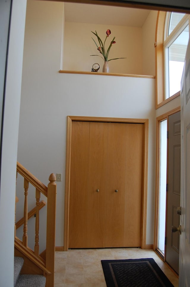 foyer entrance with light tile patterned floors, stairway, and baseboards