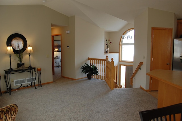 hall featuring visible vents, baseboards, carpet, vaulted ceiling, and an upstairs landing